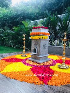 an elaborate flower arrangement on the ground with candles and flowers around it in front of some trees