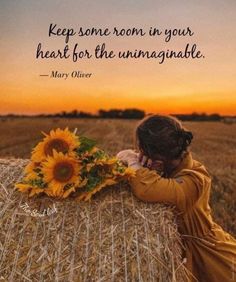 a woman in a yellow dress hugging a hay bale with a sunflower on it