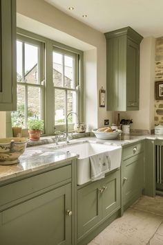 a kitchen filled with lots of green cabinets and counter top space next to a window