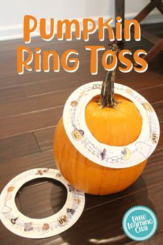 a pumpkin ring tosser sitting on top of a wooden floor next to a paper plate