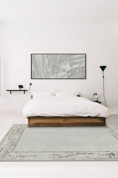 a bed sitting in the middle of a bedroom next to a wall mounted art piece