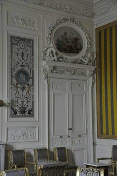 an ornately decorated room with chairs and paintings on the walls, along with striped curtains