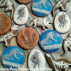 cookies decorated with dinosaurs and bones are on a wooden table in front of the words, love bugs cakes and cookies