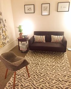 a living room with a brown couch and two chairs in front of a rug on the floor