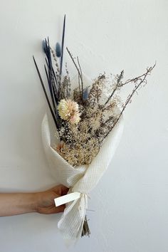 a hand holding a bouquet of dried flowers