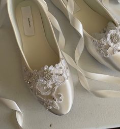 two pairs of wedding shoes with white ribbons