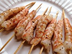 several skewers of shrimp on a white plate