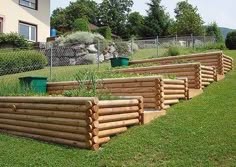 a row of wooden planters sitting on top of a lush green field next to a fence