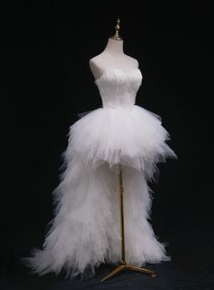 a white tulle dress on a mannequin stand in front of a black background