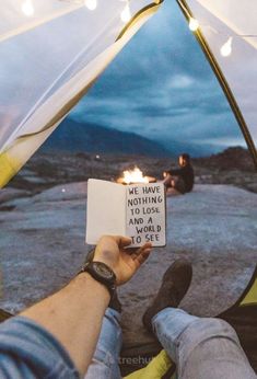 someone holding up a sign in front of a tent