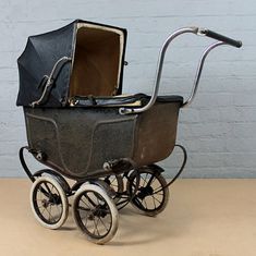 an old fashioned baby buggy is shown against a brick wall