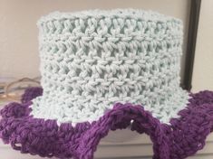 a purple and white crocheted hat sitting on top of a table