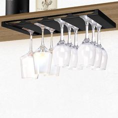 four wine glasses are hanging from a shelf