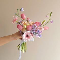 a person holding a bouquet of flowers in their hand with the stems still attached to it