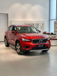 a red volvo car is parked in a showroom