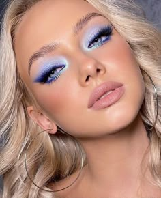 a woman with bright blue makeup and hoop earrings