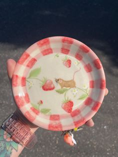 a person holding a plate with strawberries on it in their left hand and the other hand