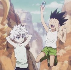 two young boys jumping in the air with their arms up and one holding a cell phone