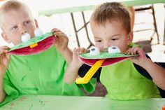 two young boys sitting at a table with paper plates in front of them, one holding a toy