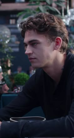 a young man sitting at a table in front of a laptop computer