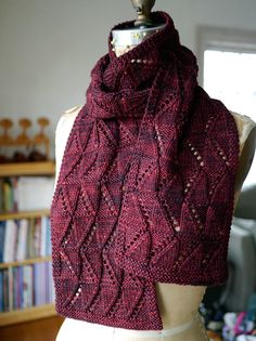 a red knitted scarf sitting on top of a mannequin