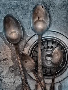 five spoons are sitting on top of a drain