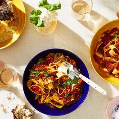 two bowls of pasta with sauce and parmesan cheese on the side next to other dishes