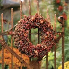 a close up of a metal gate with a wreath on it and flowers in the background