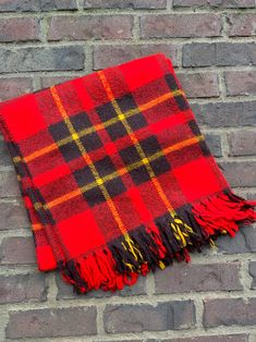 a red and black plaid blanket sitting on top of a brick wall