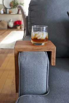 a glass filled with liquid sitting on top of a wooden table next to a gray couch