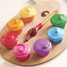 there are cupcakes with different colors on the tray next to eachother