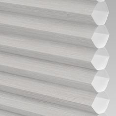 a close up view of a white roman blind with hexagonal holes