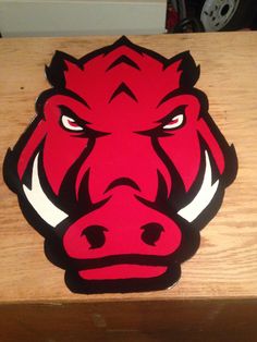 a close up of a red bull head on a wooden table with wood grain in the background