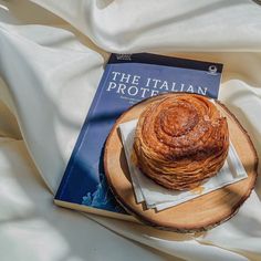 a stack of pancakes sitting on top of a wooden plate next to a book about the italian prote