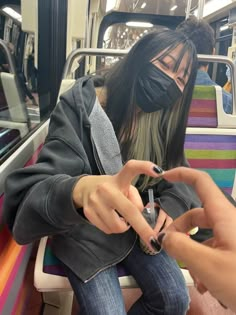 a woman sitting on a bus using her cell phone with blind folded over her face