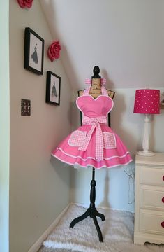 This is such a girly apron that will have you feeling all dressed up while entertaining your guests, creating your favorite culinary delights or just hanging around the house. Full circle skirt, bodice lined with pink gingham fabric, extra-long waist sashes to tie in the front or back, no raw edges. Material: 100% Cotton/ Trim: Poly/Cotton Bias Piping Measurements: Across Bodice: 14 1/2" Neck Ties: 33" Skirt Length: 16" Waist Sashes/Ties: 45" each Top of Bodice to Bottom of Skirt: 29" Fits Sizes S/M/L Best. Can be made in smaller or larger sizes, just contact me Care Instructions: Machine Wah, Cold Water, Delicate Cycle, Line Dry, Iron as Needed Petticoat is used for styling only and not included Girly Apron, Murrells Inlet Sc, Hostess Apron, Murrells Inlet, Cute Aprons, Sewing Aprons, Full Circle Skirt, Gingham Fabric, Full Circle Skirts