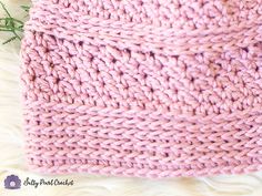 a pink knitted blanket laying on top of white fur