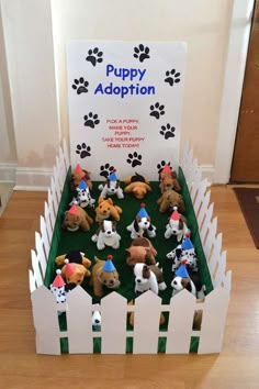 there are many small toy dogs in a box on the floor next to a sign that says puppy adoption