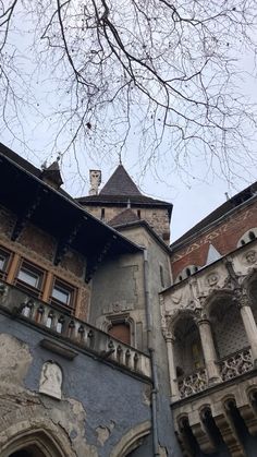 an old building with many windows and balconies on the top floor, next to a tree