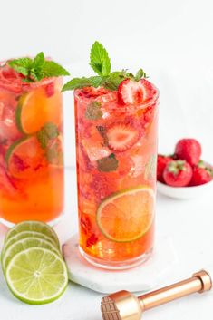 two glasses filled with strawberry lemonade and mint garnish next to strawberries