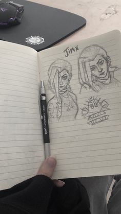 a person holding a notebook with two drawings on it and a pen in front of them