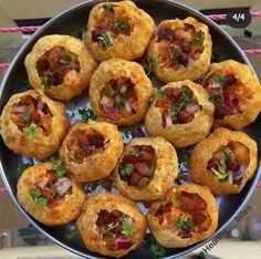 a metal bowl filled with mini pizzas on top of a table next to a pink rope