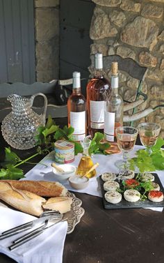 a table topped with bottles of wine and glasses filled with different types of food next to each other