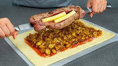 a person cutting up a large piece of meat on top of some potatoes and apples