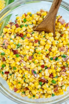 corn salad in a glass bowl with a wooden spoon