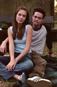 a young man and woman sitting on the ground