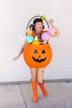 a woman dressed up as a pumpkin with candy in her hands