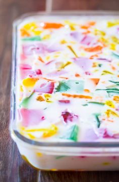 a colorful cake in a glass dish on a wooden table