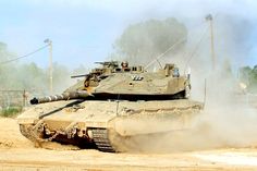 an army tank driving down a dirt road