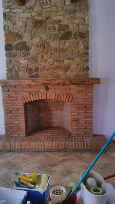 a brick fireplace in the middle of a living room with tools and other items on the floor